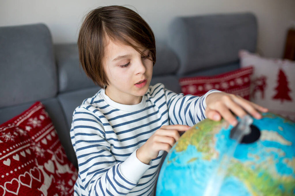 Little child, looking at illuminated globe, exploring the world, learning - Foto, afbeelding