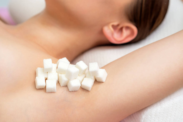 Pieces of white sugar on a woman's armpit, close up, sugaring concept. - Photo, Image