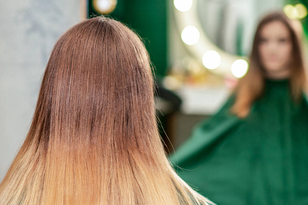 Молода жінка з новою зачіскою крупним планом сидить перед дзеркалом в перукарні
. - Фото, зображення