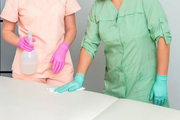 Dois cosmetologists fêmeas limpam o sofá médico antes de procedimentos de beleza
. - Foto, Imagem