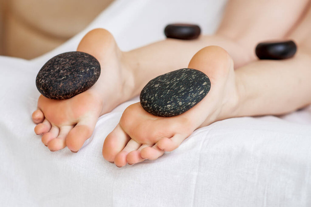 Voeten massage op benen van de vrouw door hete stenen close-up. - Foto, afbeelding