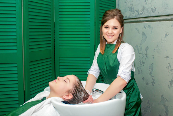 kapper wassen vrouw haar in spoelbak in schoonheidssalon. - Foto, afbeelding