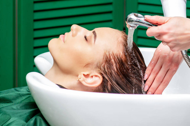 Процесс мытья волос женщины в раковине в салоне красоты крупным планом
. - Фото, изображение