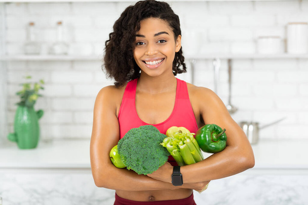 Heureuse jeune fille africaine tenant des légumes verts
 - Photo, image