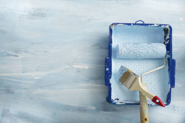 Лоток, валик і пензлик для фарбування стін на синьому фоні
 - Фото, зображення