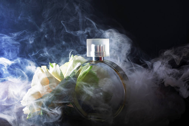 Fles parfum met bloemen in rook - Foto, afbeelding
