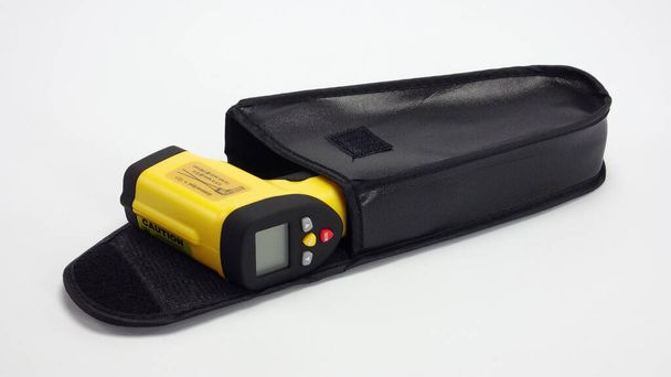Pistola de termômetro infravermelho amarelo no fundo branco
 - Foto, Imagem