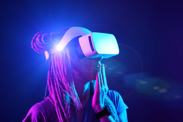Donna sta usando cuffie realtà virtuale. Neon luce studio ritratto. - Foto, immagini