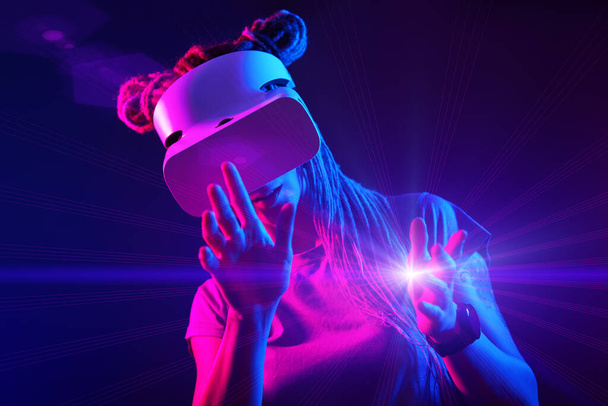 Woman is using virtual reality headset. Neon light studio portrait. - Фото, изображение