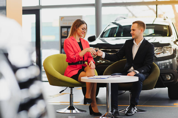 Beautiful young woman buys a car in the dealership saloon. - Valokuva, kuva