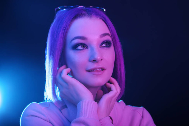 Portrait of a young woman with purple hair in a neon light. Night life. Generation Y, millennials. - 写真・画像