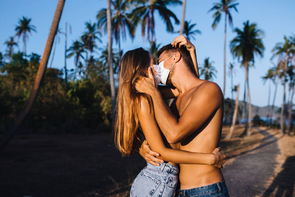 Defenselessness concept. Half-naked couple kisses on the background of palm trees - Photo, Image