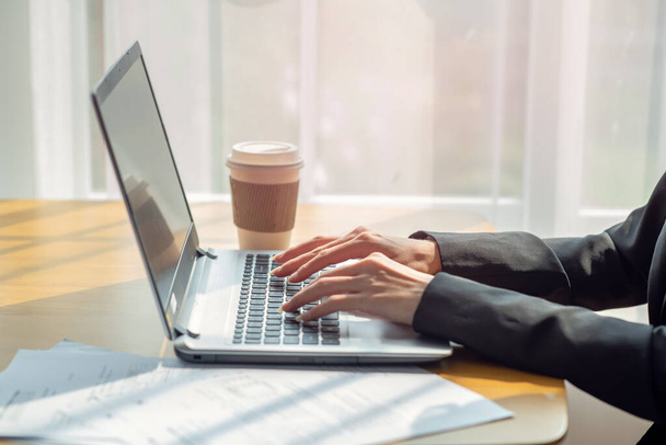 Close-up van een zakenvrouw handen typen in een laptop in het kantoor met kopje koffie, business concept - Foto, afbeelding