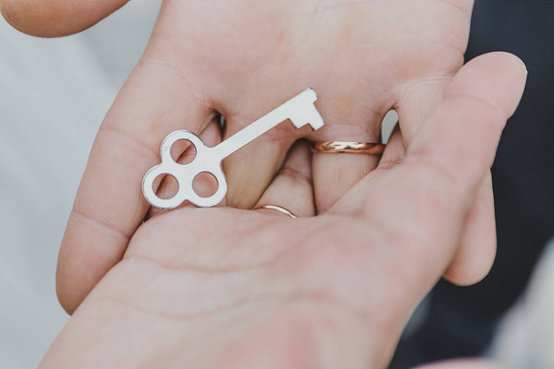 Novio y novia sosteniendo llave de cerradura en sus manos
 - Foto, Imagen