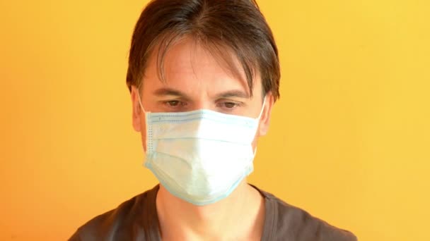 Sad man joyfully take off medical mask on yellow background, end of quarantine - Video