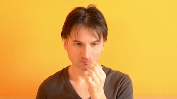 Eurooppalainen mies kutittaa nenäänsä ja aivastaa keltaisella taustalla
 - Materiaali, video