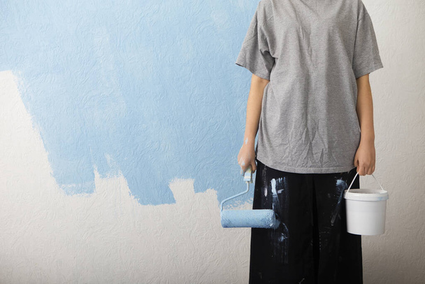 Girl with paint roller and bucket makes repairs - 写真・画像