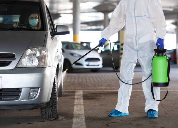 Personne méconnaissable désinfectant voiture avec pulvérisation avec femme à l'intérieur
 - Photo, image