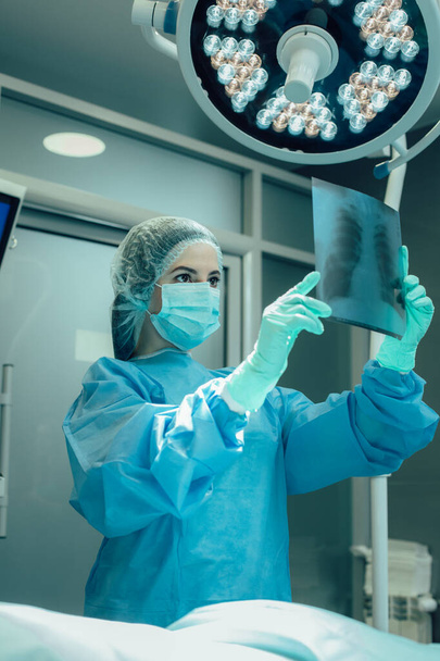 Woman in medical uniform holding chest x ray in the operation room. Pneumonia concept - Foto, Bild