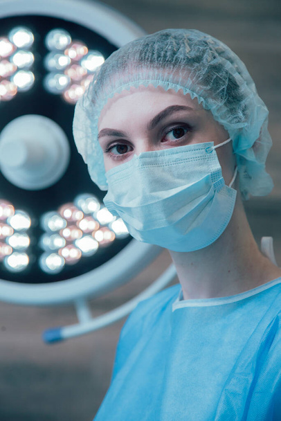 Young female doctor wearing medical mask in the operating theatre - Foto, Bild