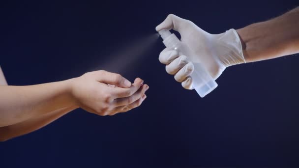 手を閉じると、白い医療用手袋の男は、予防コロナウイルスの流行の予防、消毒、細菌、ウイルス保護のために女の子の手に消毒剤を噴霧. - 映像、動画
