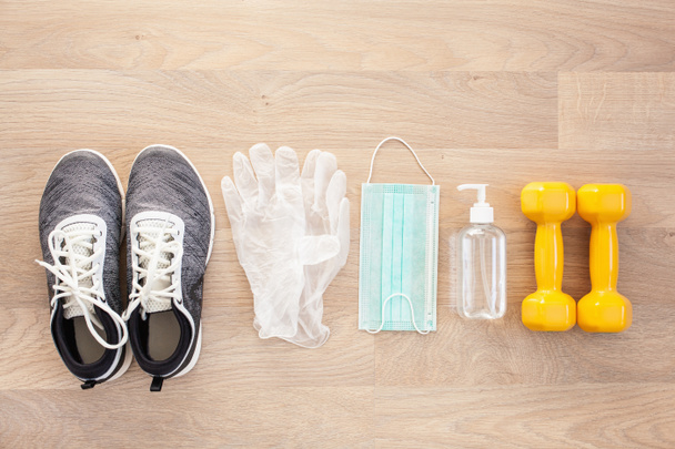 beschermende medische masker ontsmettingsgel handschoenen. home fitness training sneakers halter en beschermende maatregelen tegen virus, bacteriën - Foto, afbeelding