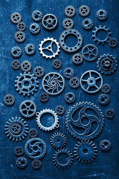trendkleur van het jaar 2020 klassiek blauw. steampunk mechanische tandwielen tandwielen op houten achtergrond - Foto, afbeelding