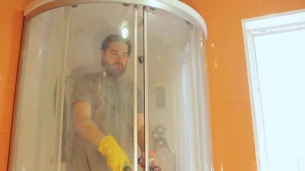 Санитарная чистка душевой кабины для безопасности дома во время коронавируса.Человек в футболке и бороде, дезинфицирует ванную комнату.Сильная иммунная система для хорошего иммунитета.
 - Кадры, видео
