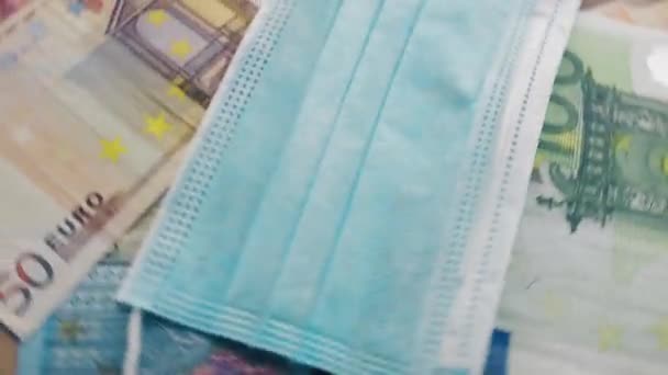 Spinning Euro banknotes and gauze mask. COVID-19 pandemia, economic crisis, default, healthcare or business concept. - Felvétel, videó
