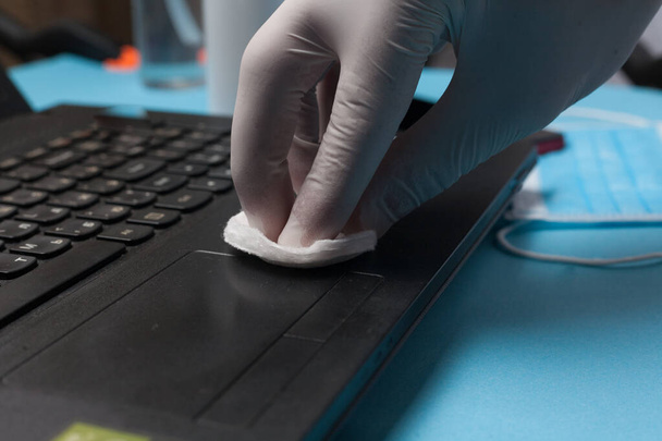 Zbliżenie dezynfekcji laptopa w białych rękawiczkach. Zapobieganie zakażeniom koronawirusami. - Zdjęcie, obraz