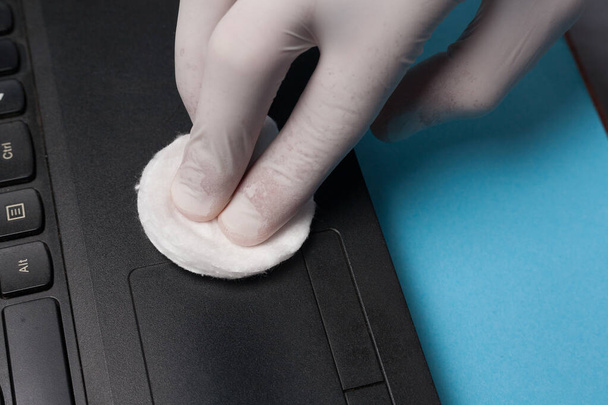 Nahaufnahme der Desinfektion beim Reinigen eines Laptops in weißen Handschuhen. Prävention von Coronavirus-Infektionen. - Foto, Bild