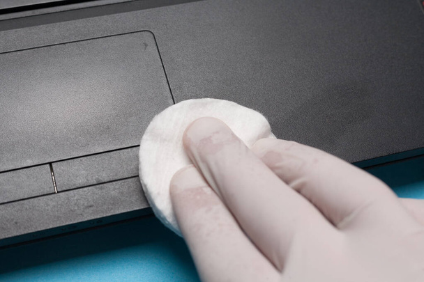 Nahaufnahme der Desinfektion beim Reinigen eines Laptops in weißen Handschuhen. Prävention von Coronavirus-Infektionen. - Foto, Bild