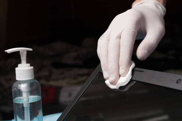 消毒のクローズアップ白い手袋でラップトップを掃除します。コロナウイルス感染の予防. - 写真・画像