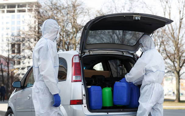 Familie in virusbeschermende pakken die ontsmettingsmiddelen kopen - Foto, afbeelding