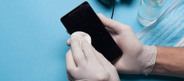 Close-up of disinfection, cleaning smartphone in white gloves. Prevention of coronavirus infection.Close-up of disinfection, cleaning smartphone in white gloves. Prevention of coronavirus infection. - Фото, изображение