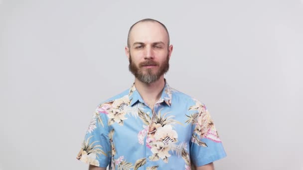 Πορτρέτο του ήρεμου γενειοφόρου άνδρα κοιτάζοντας κάμερα φορώντας hawaiian πουκάμισο, απομονώνονται σε λευκό φόντο. Έννοια των συναισθημάτων. - Πλάνα, βίντεο