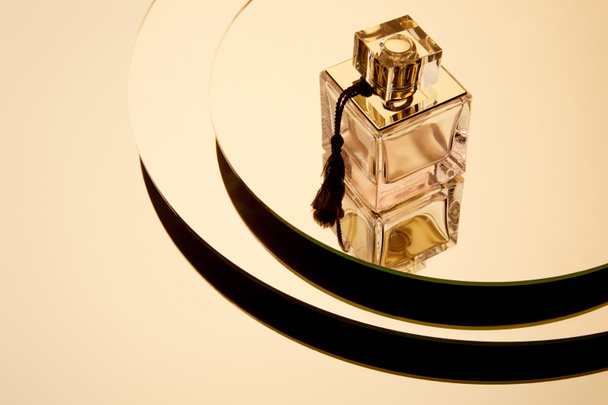 Vista de ángulo alto de la botella de perfume de lujo en la superficie redonda espejo con reflexión
 - Foto, Imagen