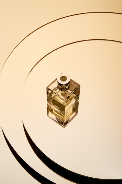 Vista de ángulo alto de la botella de perfume de oro en la superficie redonda espejo con reflexión
 - Foto, Imagen