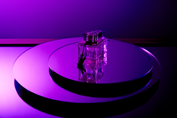 Frascos de perfume de lujo violeta en superficie redonda espejo con reflejo aislado en púrpura
 - Foto, Imagen