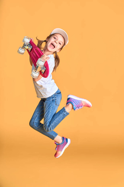 Active and happy. Kid having fun with penny board. Child smiling face stand skateboard. Penny board cute skateboard for girls. Lets ride. Girl ride penny board white background. Summer vacation - Фото, зображення