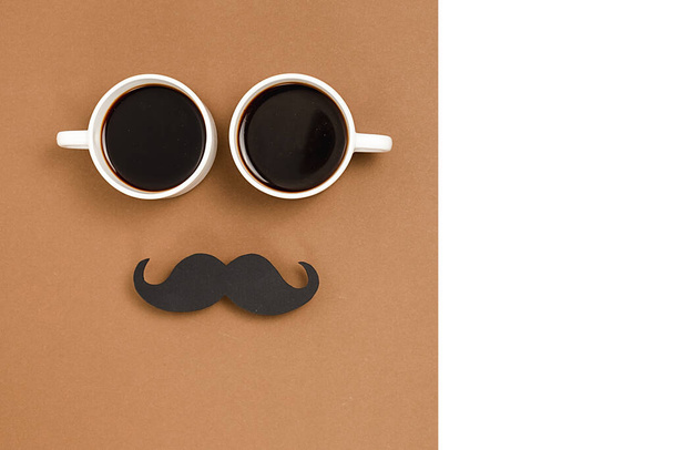 Two cup coffee, stylish black paper photo booth props moustaches on brown and white background. Copy space for inscriptions. Holiday Concept. - Fotó, kép