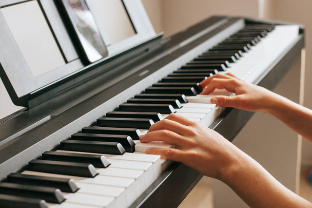 Concept of quarantine during a novel coronavirus infection, social distance, home education. CHILD LEARNS TO PLAY THE PIANO ONLINE - Photo, Image