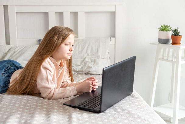Schoolgirl using laptop computer at home. Distance learning, online education, home education, quarantine concept. - Fotó, kép