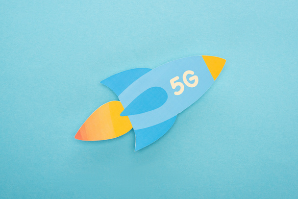 top view of paper rocket with 5g lettering on blue background - Φωτογραφία, εικόνα