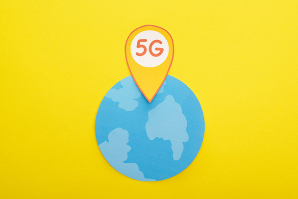 top view of globe and 5g lettering in location mark on yellow background - Photo, Image