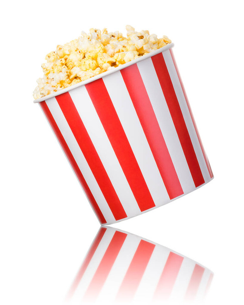 Paper striped bucket with popcorn isolated on white background with clipping path. Concept of cinema or watching TV. - Photo, image