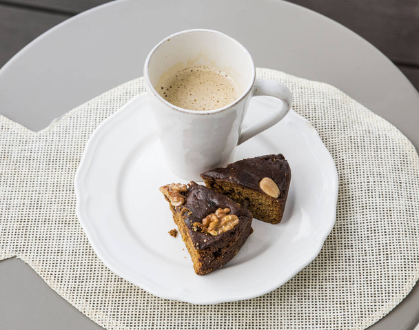Dva plátky Bolo de mel je tradiční dort z Madeiry na bílém talíři, bílý šálek kávy na pozadí. - Fotografie, Obrázek