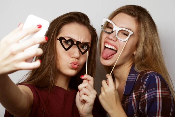 lifestyle, party and people concept: two stylish sexy hipster girls best friends ready for party, over white background - 写真・画像