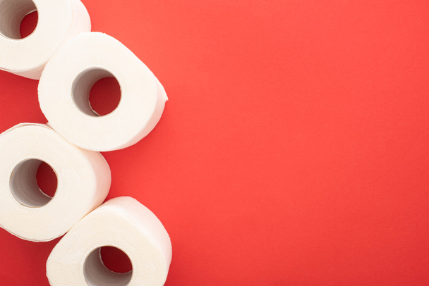 Horní pohled na bílé toaletní papír role na červeném pozadí s kopírovacím prostorem - Fotografie, Obrázek