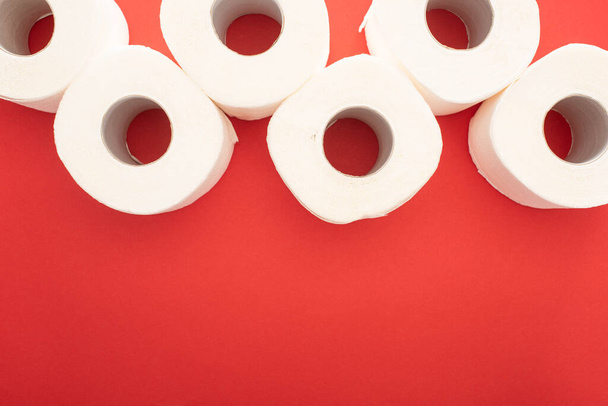 top view of white toilet paper rolls on red background with copy space - Foto, imagen